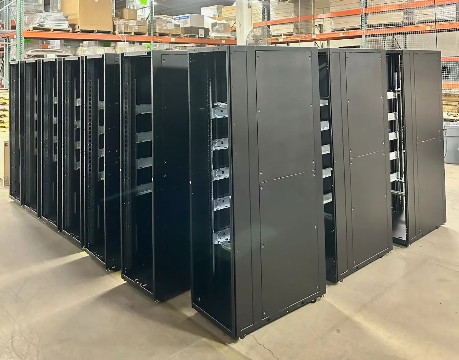 Rows of black server rack enclosures staged on the production floor