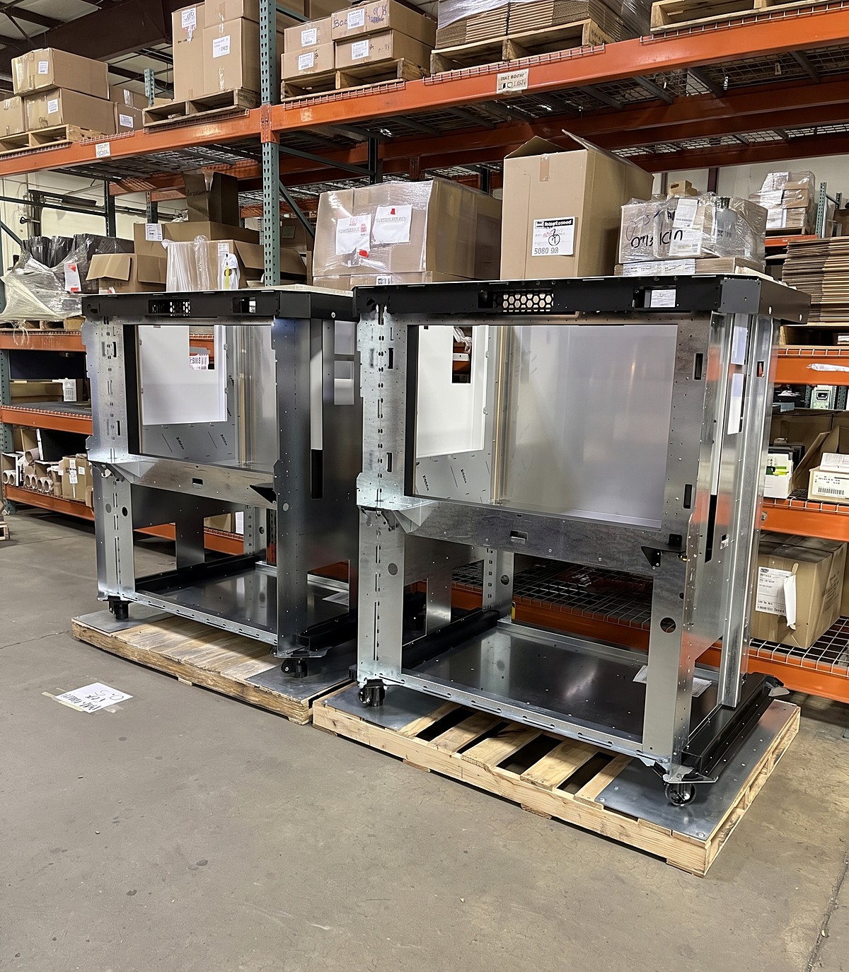 The finished cart frames built and staged on pallets, the same assembly shown as a CAD model beside it