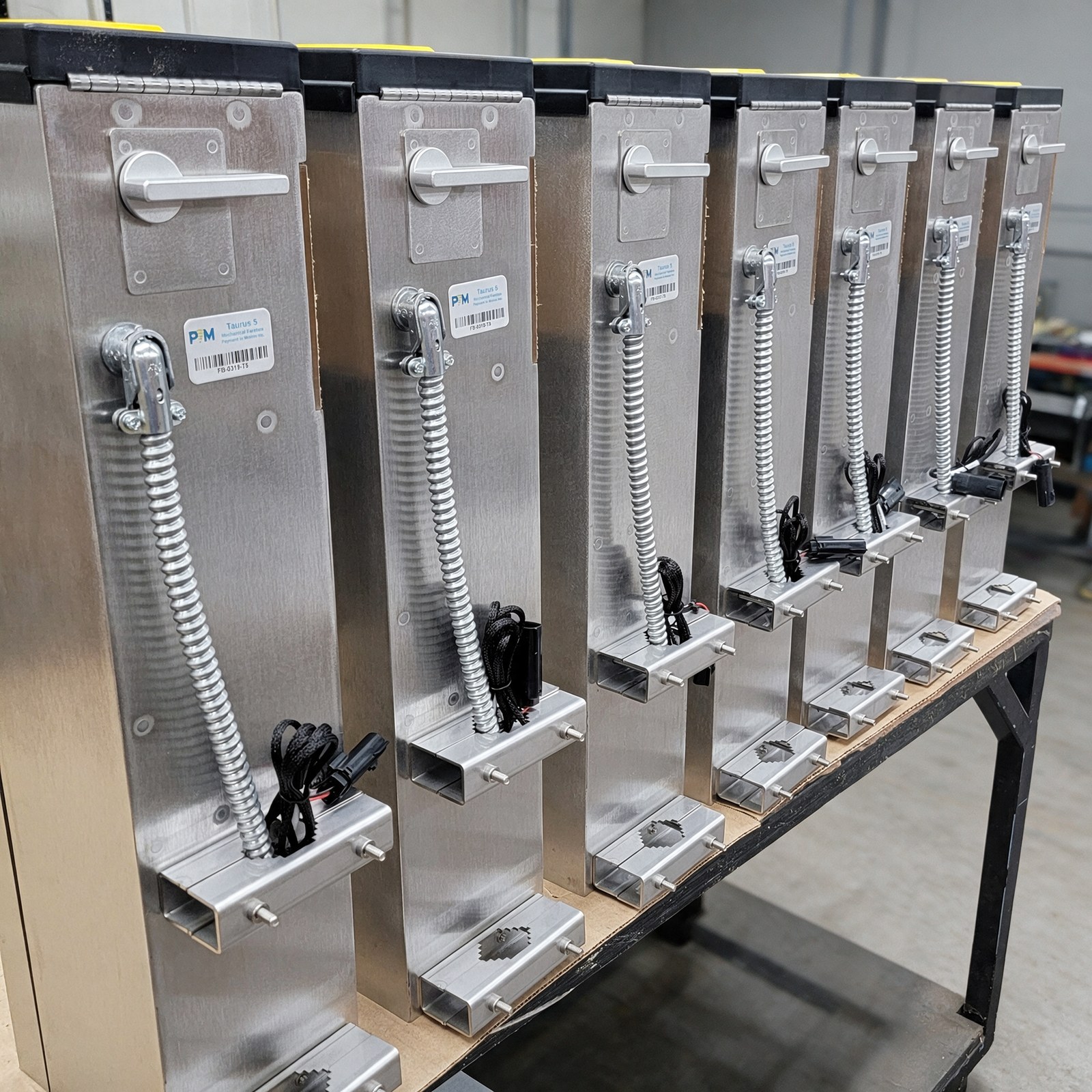 A run of identical stainless steel dispenser assemblies lined up on the bench